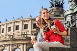 Zwei Touristinnen sitzen vor der Semper Omper und trinken einen Kaffee