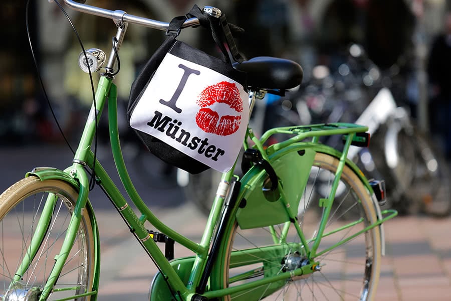 Grünes Fahrrad mit einer Münster-Tasche am Lenkrad