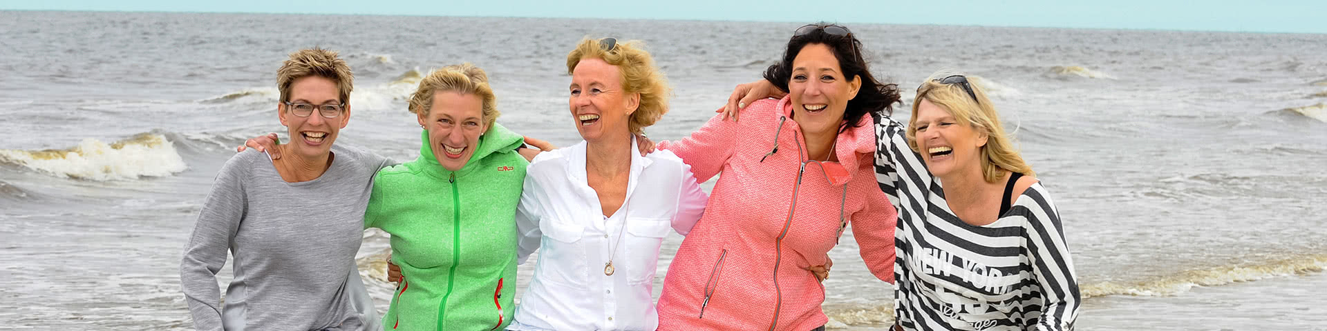 Gut gelaunte Frauengruppe steht am Meer auf Norderney